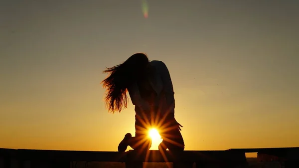 Junges Mädchen in Sportuniform sitzt bei Sonnenuntergang auf dem Dachrand. — Stockfoto