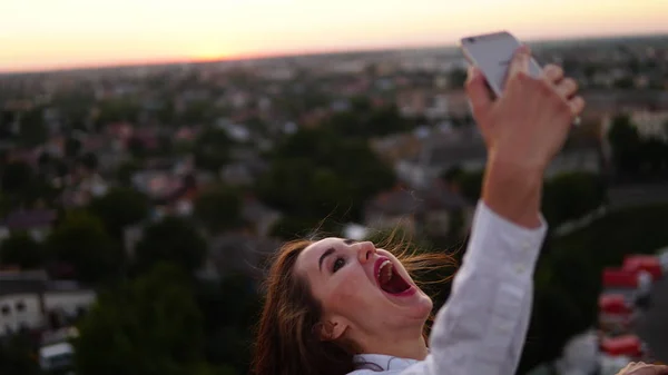 Outdoor portrait of beautiful girl taking a selfie on the roof. — Stock Photo, Image