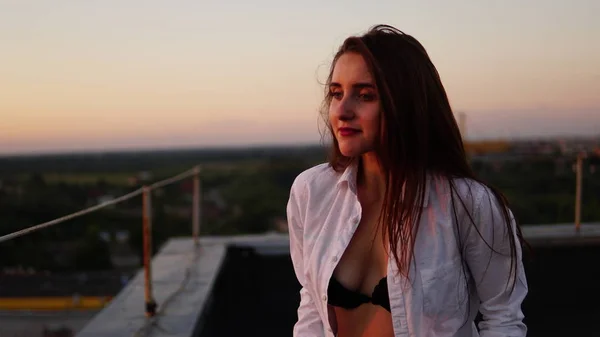 Giovane ragazza in uniforme sportiva si siede sul bordo del tetto durante il tramonto . — Foto Stock