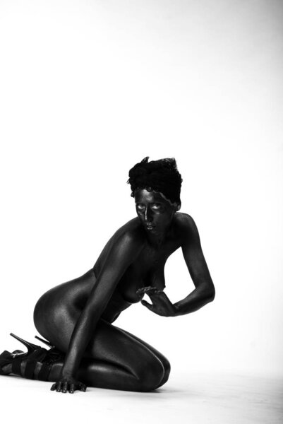 Naked woman painted in black on a white background in the studio,