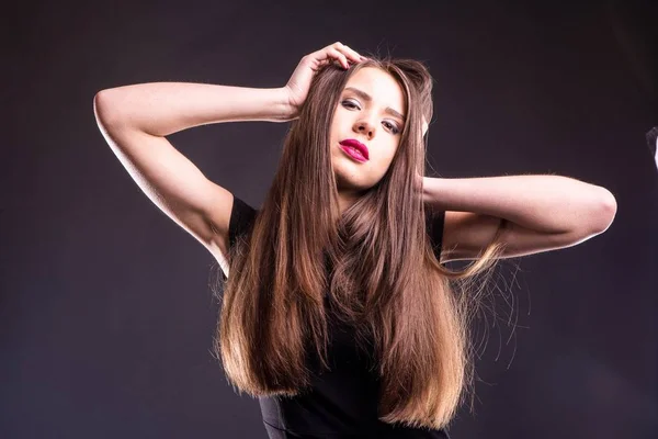 Retrato de uma bela jovem mulher em um vestido preto com uma maquiagem legal e boa pele. Estúdio, fundo preto . — Fotografia de Stock