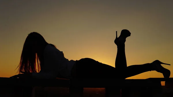 Chica joven en uniforme deportivo se sienta en el borde del techo durante el atardecer . —  Fotos de Stock