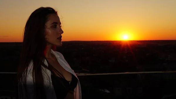 Chica joven en uniforme deportivo se sienta en el borde del techo durante el atardecer . —  Fotos de Stock