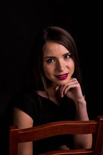 Retrato de uma bela jovem mulher em um vestido preto com uma maquiagem legal e boa pele. Estúdio, fundo preto . — Fotografia de Stock