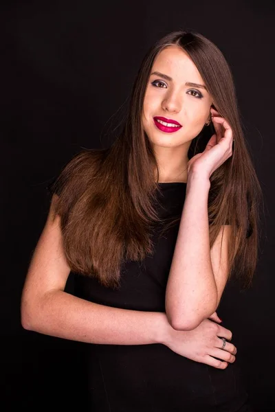 Retrato de uma bela jovem mulher em um vestido preto com uma maquiagem legal e boa pele. Estúdio, fundo preto . — Fotografia de Stock