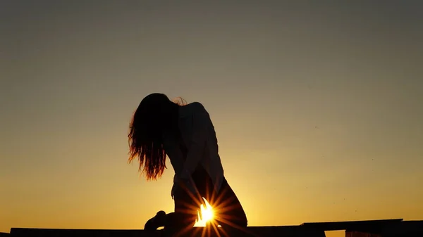 Menina jovem em uniforme esportivo senta-se na borda do telhado durante o pôr do sol . — Fotografia de Stock