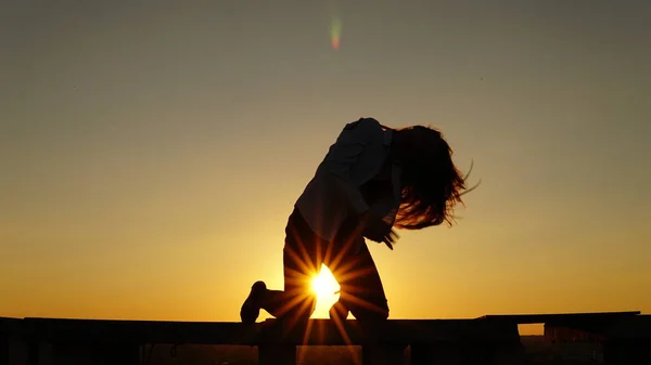 Junges Mädchen in Sportuniform sitzt bei Sonnenuntergang auf dem Dachrand. — Stockfoto