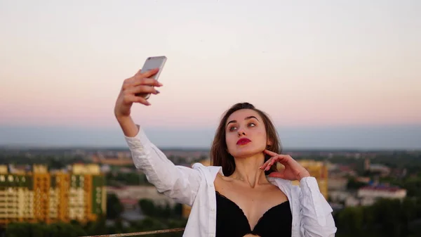 Outdoor portrait of beautiful girl taking a selfie on the roof. — Stock Photo, Image