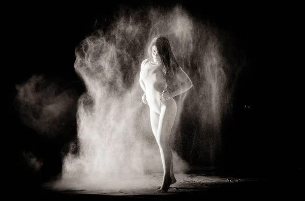La chica con la harina en el cuerpo estira los brazos con harina tirada sobre fondo negro imagen en blanco y negro — Foto de Stock
