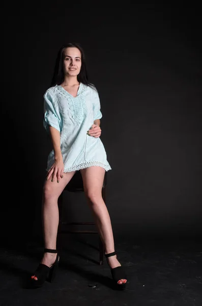 Mulher bonita nova com cabelo encaracolado preto longo posando em vestido de noite azul. Menina deslumbrante lindo em pé no interior escuro. Retrato de moda estilo moda . — Fotografia de Stock