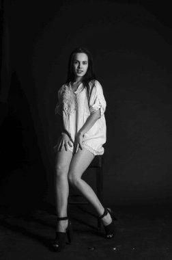 Mavi gece elbisesi poz uzun siyah kıvırcık saçlı genç güzel kadın. Muhteşem çarpıcı kız karanlık iç ayakta. Moda moda tarzı portre