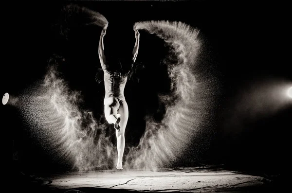 La fille avec la farine sur le corps étire les bras vers le haut avec de la farine jetée sur fond noir image noir et blanc — Photo