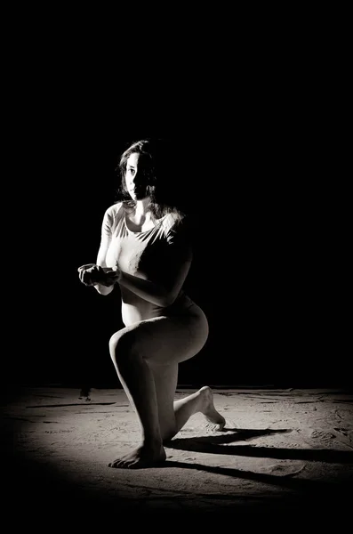 La fille avec la farine sur le corps étire les bras vers le haut avec de la farine jetée sur fond noir image noir et blanc — Photo