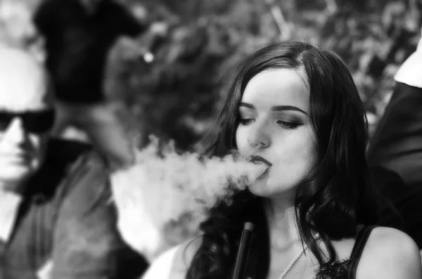 Sexy girl with smartphone smokes hookah