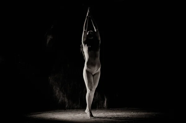Девушка с мукой на теле протягивает руки вверх с брошенной мукой на черном фоне черно-белое изображение — стоковое фото