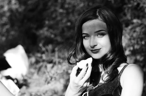 Zwart-wit fotografie van luxe grappige mooie jonge dame met verleidelijke lippen en gemanicuurde nagels eten snoep op lichte kopieerruimte achtergrond, close-up portret. — Stockfoto