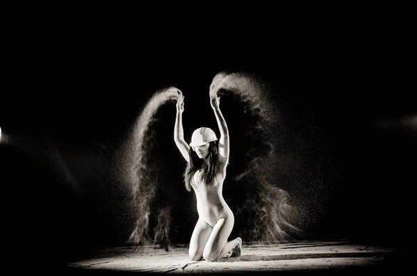 La fille avec la farine sur le corps étire les bras vers le haut avec de la farine jetée sur fond noir image noir et blanc — Photo