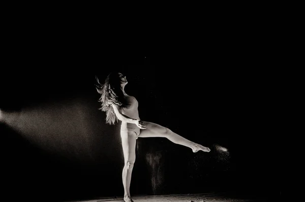 La chica con la harina en el cuerpo estira los brazos con harina tirada sobre fondo negro imagen en blanco y negro — Foto de Stock