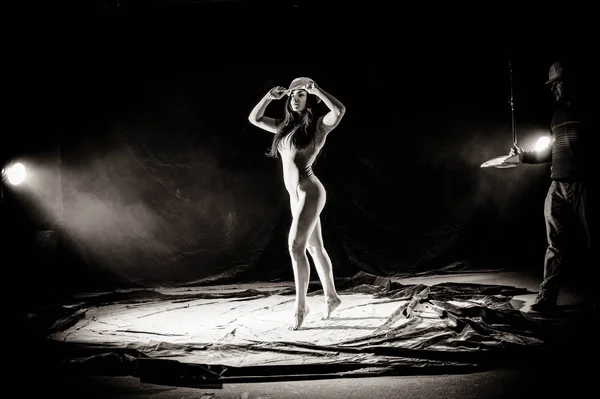 The girl with the flour on the body stretches the arms up with thrown flour on black background black and white image — Stock Photo, Image