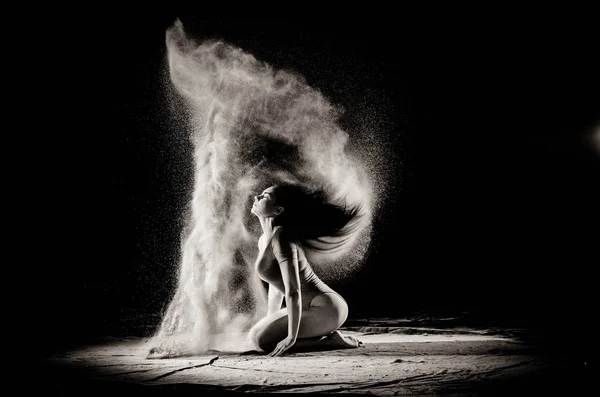 Das Mädchen mit dem Mehl auf dem Körper streckt die Arme mit geworfen Mehl auf schwarzem Hintergrund Schwarz-Weiß-Bild — Stockfoto