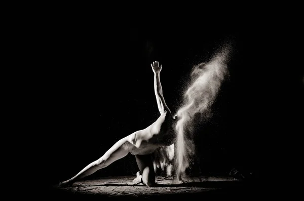 La ragazza con la farina sul corpo allunga le braccia con farina gettata su sfondo nero immagine in bianco e nero — Foto Stock