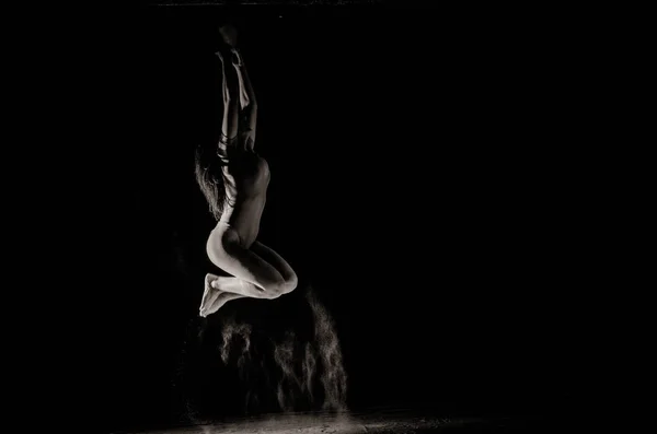 A lány a lisztet a test húzódik a karok fel dobott lisztet fekete háttér fekete-fehér kép — Stock Fotó