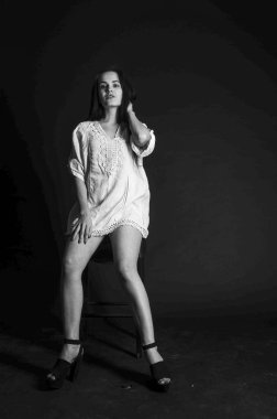 Mavi gece elbisesi poz uzun siyah kıvırcık saçlı genç güzel kadın. Muhteşem çarpıcı kız karanlık iç ayakta. Moda moda tarzı portre