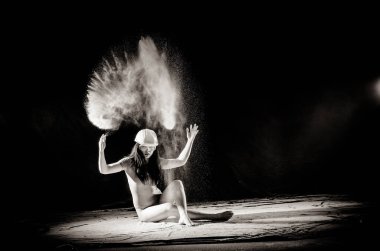 Vücudunda un ile kız siyah arka plan siyah beyaz görüntü üzerine atılan un ile kollarını yukarı uzatır