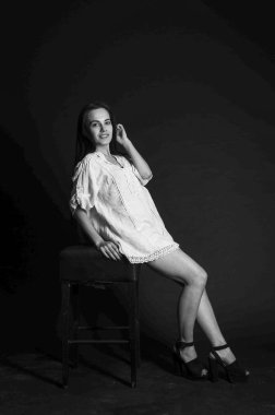 Mavi gece elbisesi poz uzun siyah kıvırcık saçlı genç güzel kadın. Muhteşem çarpıcı kız karanlık iç ayakta. Moda moda tarzı portre