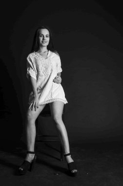 Mavi gece elbisesi poz uzun siyah kıvırcık saçlı genç güzel kadın. Muhteşem çarpıcı kız karanlık iç ayakta. Moda moda tarzı portre