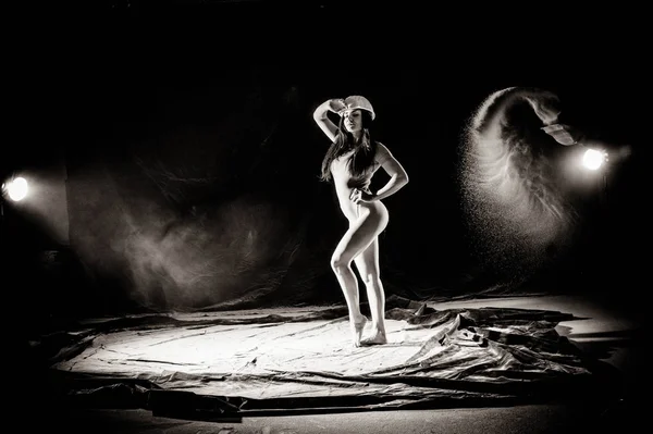 The girl with the flour on the body stretches the arms up with thrown flour on black background black and white image — Stock Photo, Image