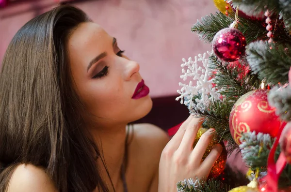 밝은 크리스마스 배경에 따뜻한 스웨터에 밝은 메이크업놀라운 우아한 매력적인 여자의 아름다움 초상화를 닫습니다. 완벽한 물결 모양의 헤어 스타일 . — 스톡 사진