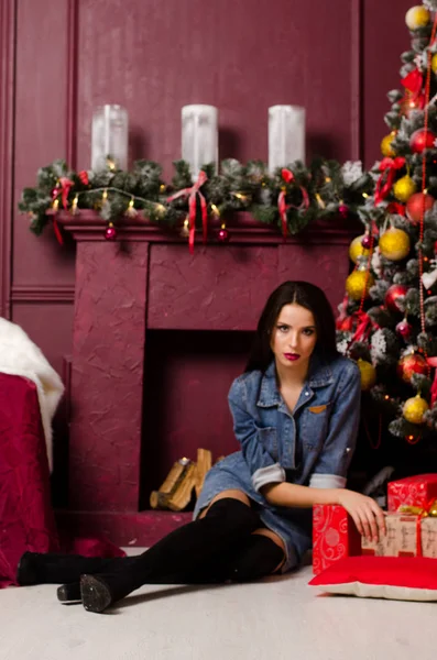 Schöne glückliche junge Mädchen liegt unter einem Weihnachtsbaum in Erwartung eines Neujahrsgeschenks — Stockfoto