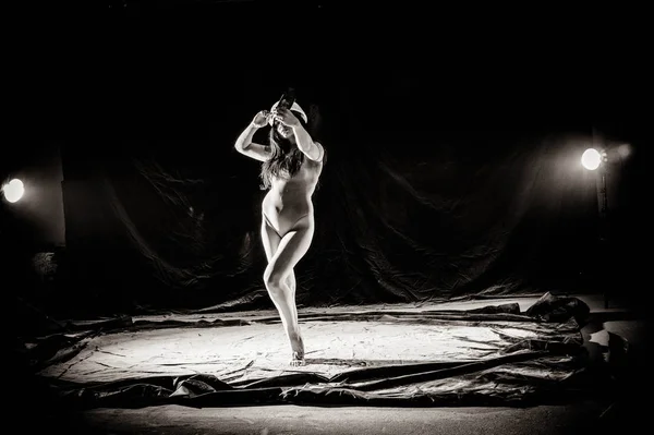 The girl with the flour on the body stretches the arms up with thrown flour on black background black and white image — Stock Photo, Image