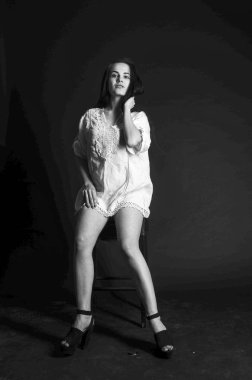 Mavi gece elbisesi poz uzun siyah kıvırcık saçlı genç güzel kadın. Muhteşem çarpıcı kız karanlık iç ayakta. Moda moda tarzı portre