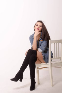 Çekici esmer güzellik sandalyede oturuyor.