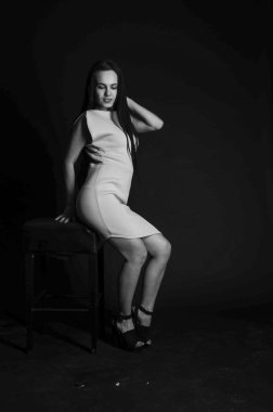 Mavi gece elbisesi poz uzun siyah kıvırcık saçlı genç güzel kadın. Muhteşem çarpıcı kız karanlık iç ayakta. Moda moda tarzı portre