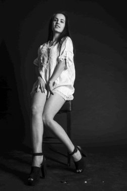 Mavi gece elbisesi poz uzun siyah kıvırcık saçlı genç güzel kadın. Muhteşem çarpıcı kız karanlık iç ayakta. Moda moda tarzı portre