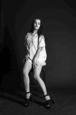 Mavi gece elbisesi poz uzun siyah kıvırcık saçlı genç güzel kadın. Muhteşem çarpıcı kız karanlık iç ayakta. Moda moda tarzı portre