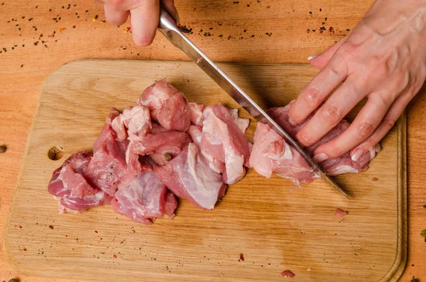 Руки женщины с ножом в руке режут свежее мясо на столе — стоковое фото