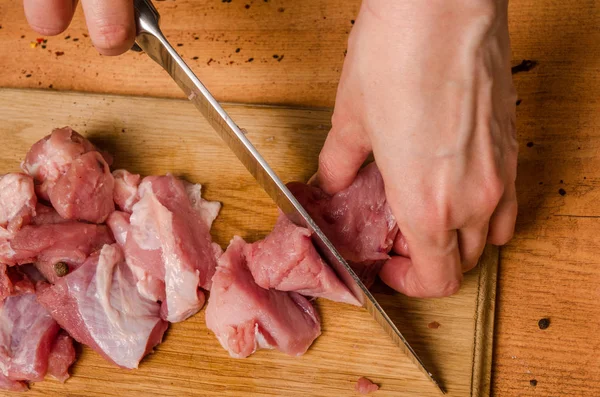 Las manos femeninas con un cuchillo en la mano cortan carne fresca en una mesa — Foto de Stock