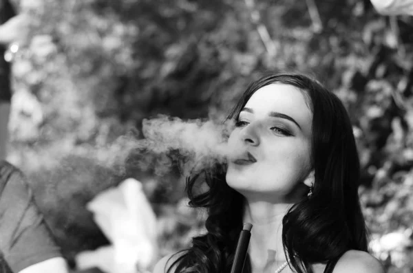 Sexy girl with smartphone smokes hookah