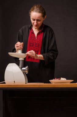 Kadın mutfakta kıyma makinesi kullanarak kıyma hazırlıyor.