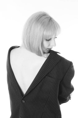 Beyaz stüdyo arka planında yalnız poz veren erkek ceketli seksi genç kadın.  