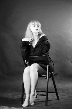 Stüdyonun arka planında erkek ceketiyle poz veren seksi, güzel bir kadın. 