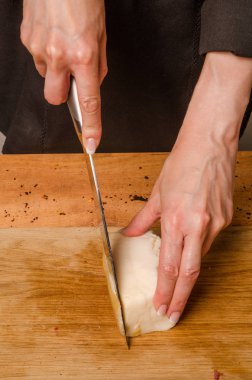 Bir kadın mutfakta füme et kesiyor..