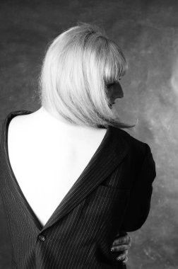 Karanlık stüdyo arka planında poz veren erkek ceketli güzel bir kadın. 