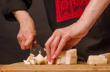 Bir kadın mutfakta füme et kesiyor..