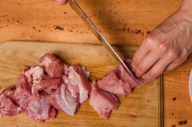 Onların elinde bir bıçak ile eller taze et bir masaya kesilmiş.