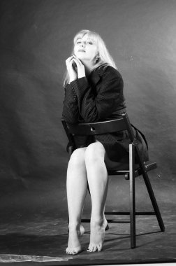 Stüdyonun arka planında erkek ceketiyle poz veren seksi, güzel bir kadın. 